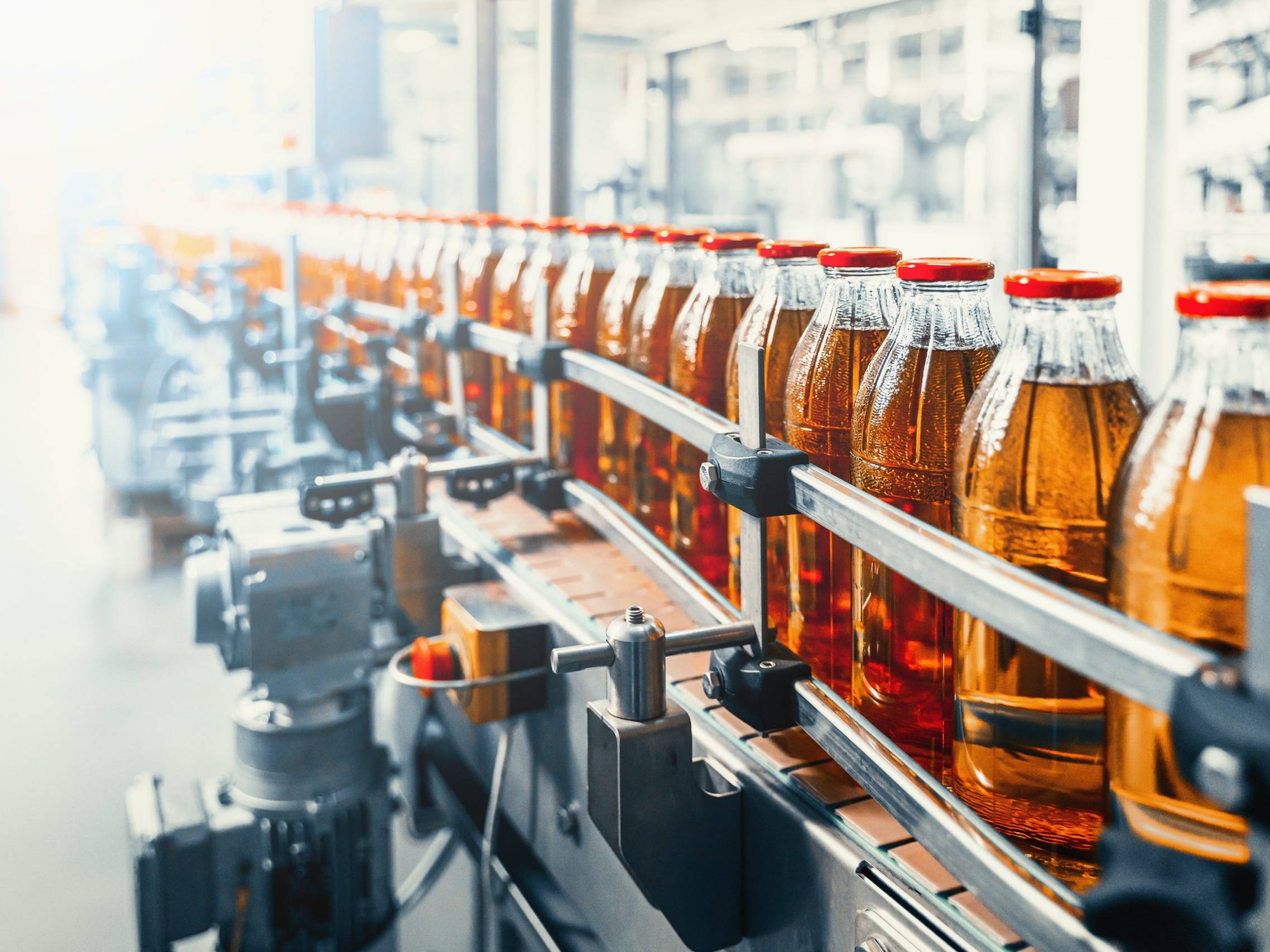 juice in glass bottles on beverage plant or factory interior, industrial manufacturing production line
