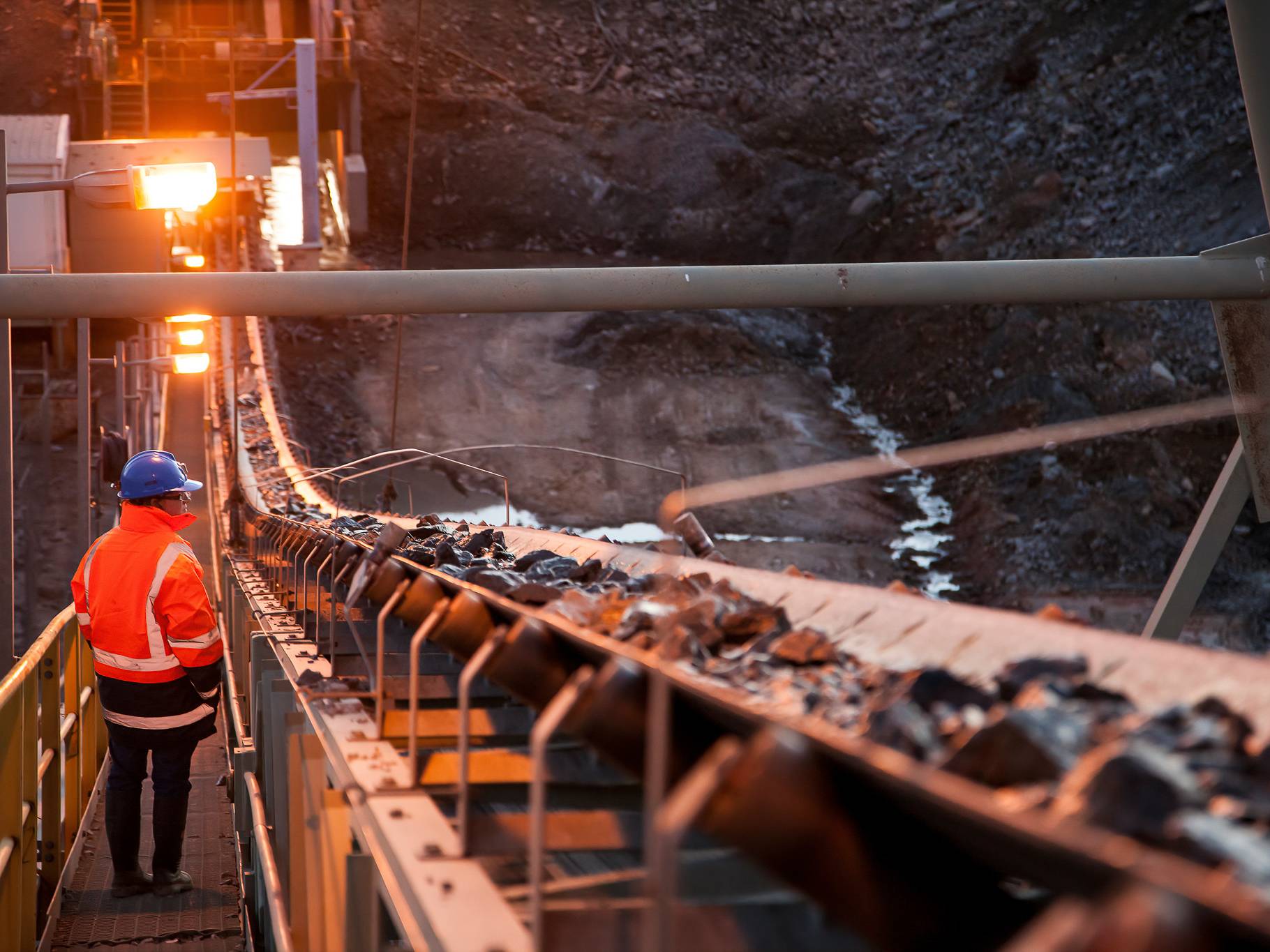 miner inspecting ore rocks on a conveyor